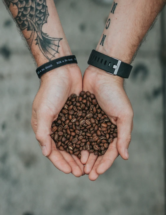 a person holding their hands over a handful of coffee beans