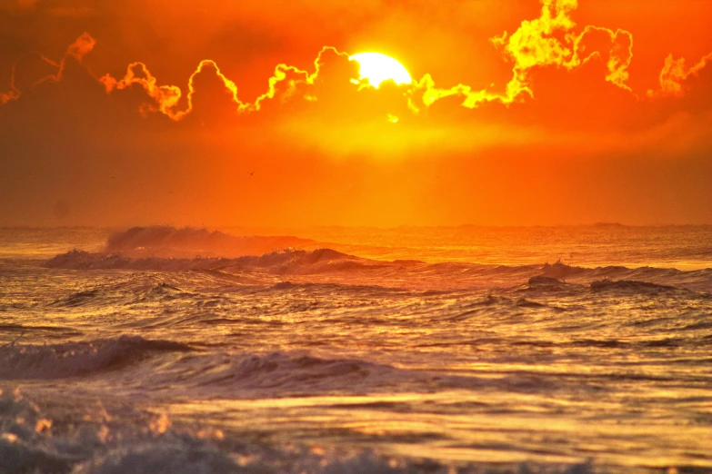 the sun set with an orange and yellow cloud over water