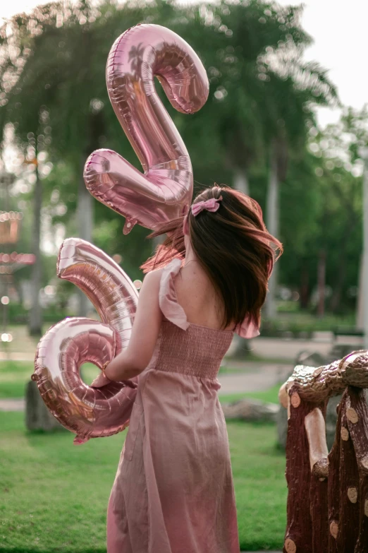 a girl holding up a number 5 balloon