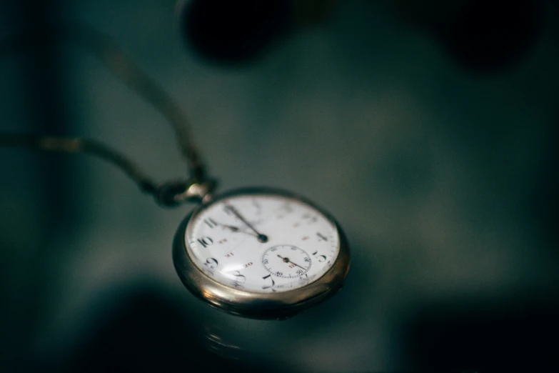 a small white pocket watch necklace hanging from a string