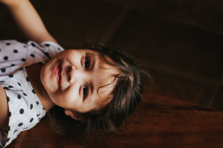 a little girl smiling at the camera on a wooden floor