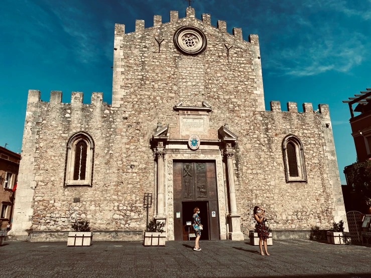 two people stand outside a very old castle like structure