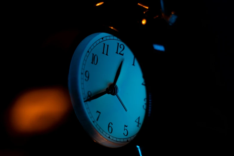 an analog clock lit up against the dark