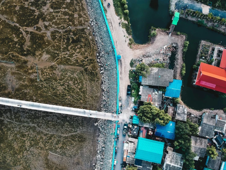 an overhead view of houses with large blue roofs and water in the foreground