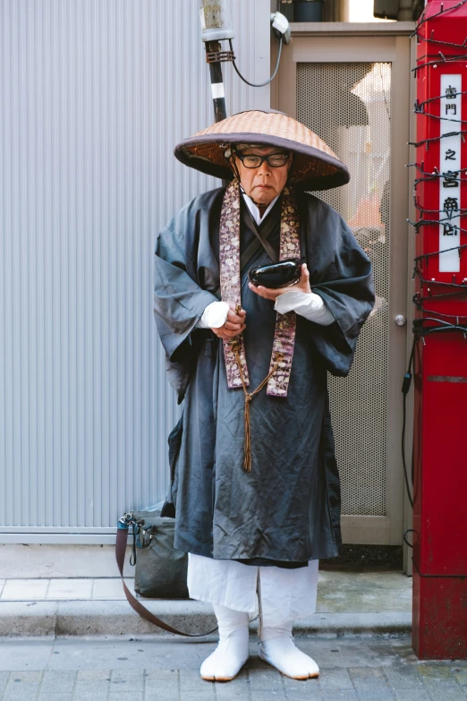 a man in an asian costume stands on the sidewalk