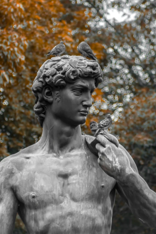 a statue holds a bird and two birds on its shoulder