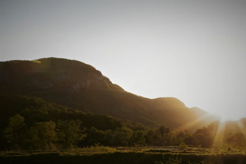 sun peeking through the mountain to see what is going on