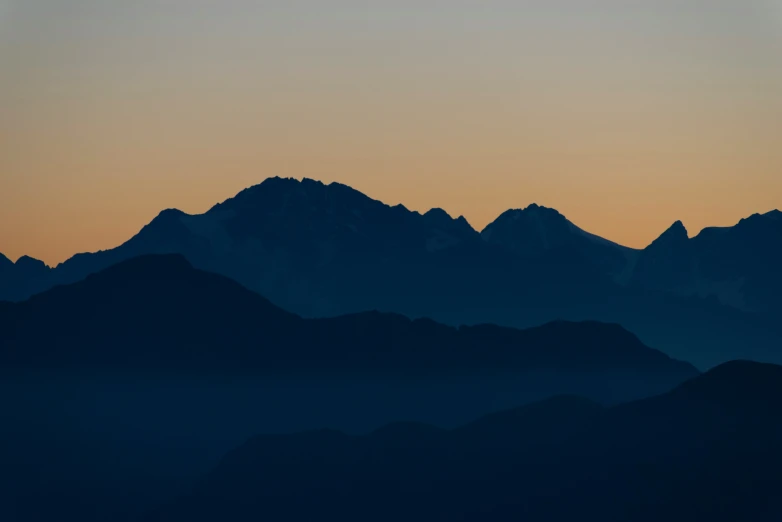 a bird flies over the top of mountains at sunset