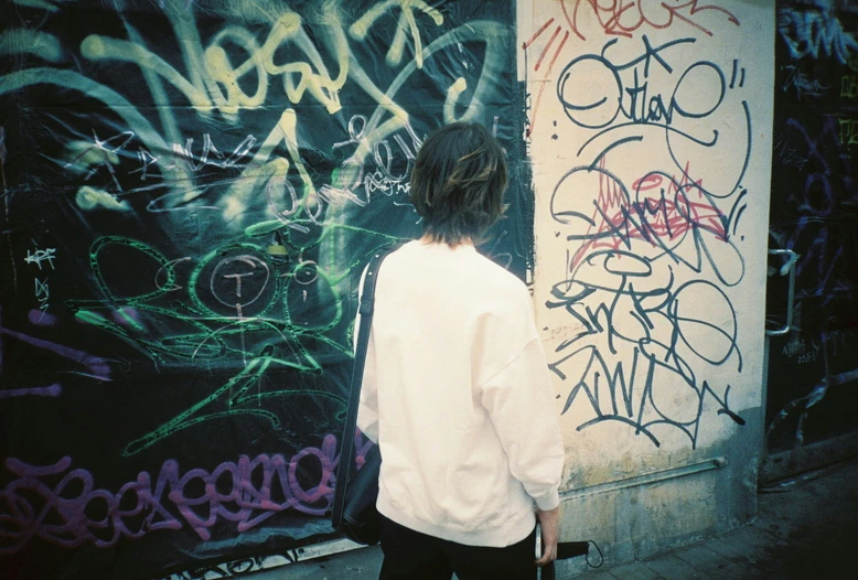 man walking down a sidewalk by graffiti covered walls