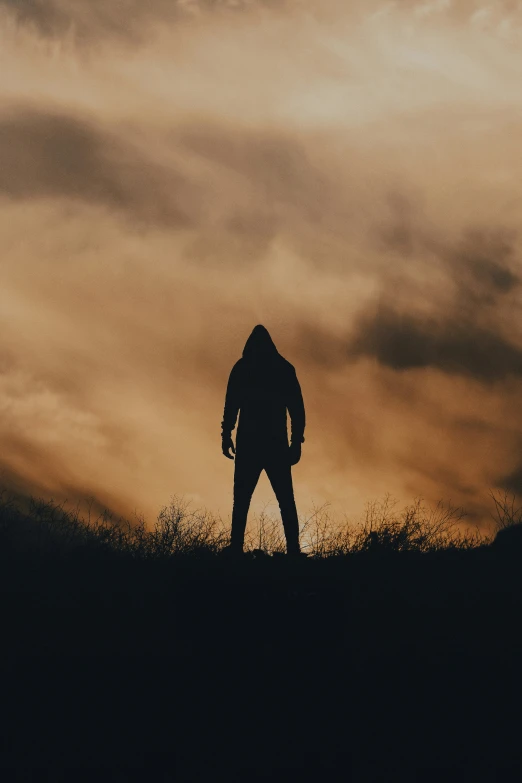 a person is standing on top of a hill with a cloudy sky in the background