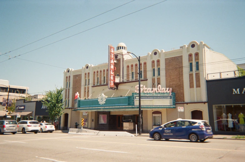 a car parked in front of a movie theater on a city street