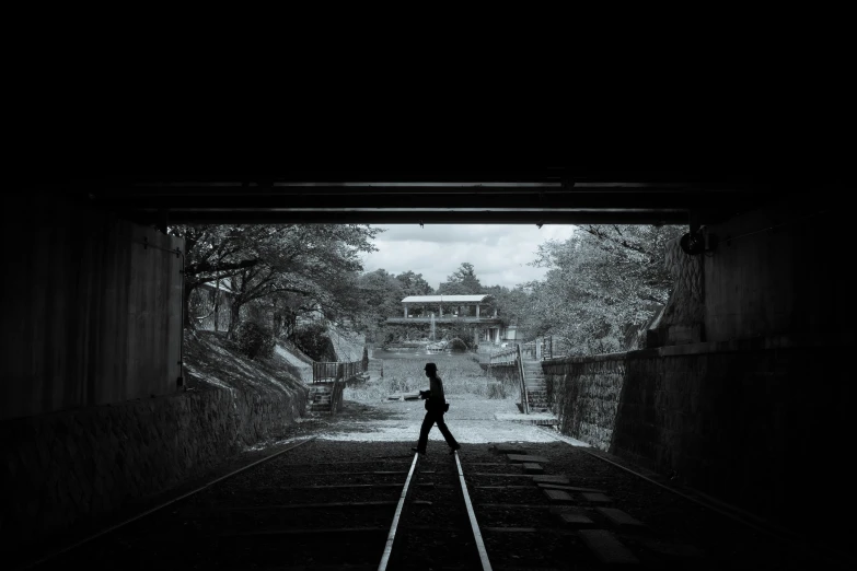 man walking down train tracks in the rain