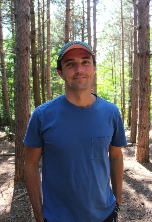 a man in a hat standing in the woods