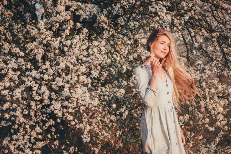 a beautiful woman posing near flowers with her hands in her pocket