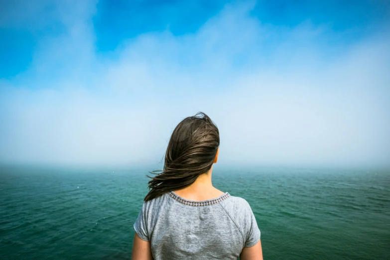 a woman stands in the water looking at the sky