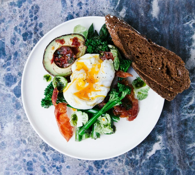 a plate filled with vegetables, an egg and a piece of bread