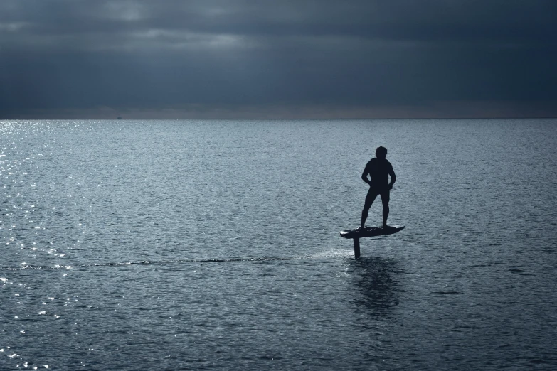 a man standing on a surfboard in a large body of water