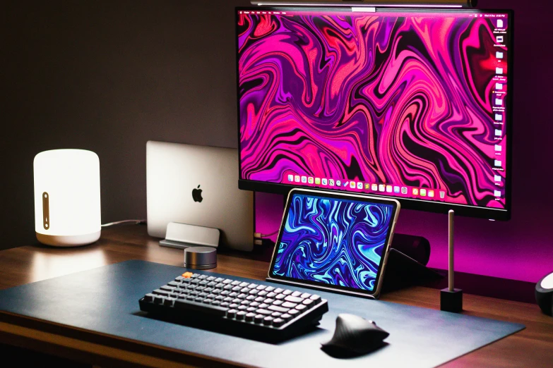 a purple and black desk top computer with a laptop on it