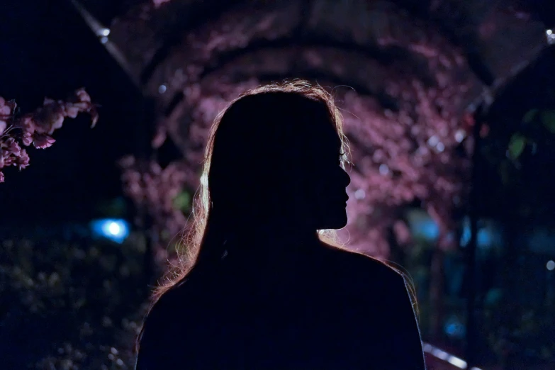 a profile s of a person looking down with trees in the background