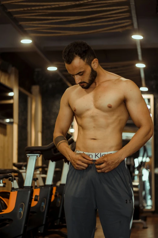 a shirtless man walks on a treadmill