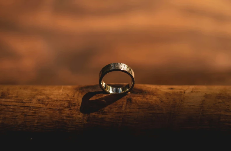 a silver ring on a wooden surface with only one side visible