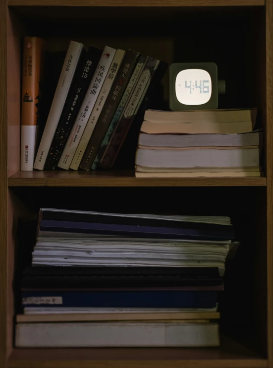 several books and electronic items sitting on top of a bookcase