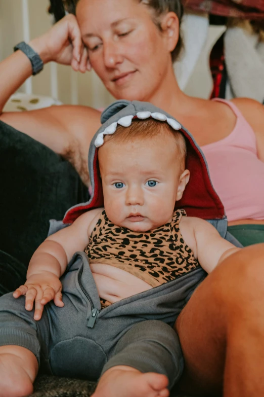 a little baby with blue eyes sitting in a woman's lap