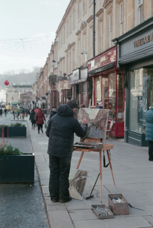 someone painting a picture on an easel in front of a busy street