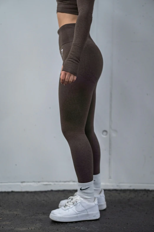 woman in tight leggings and sneakers standing by the wall