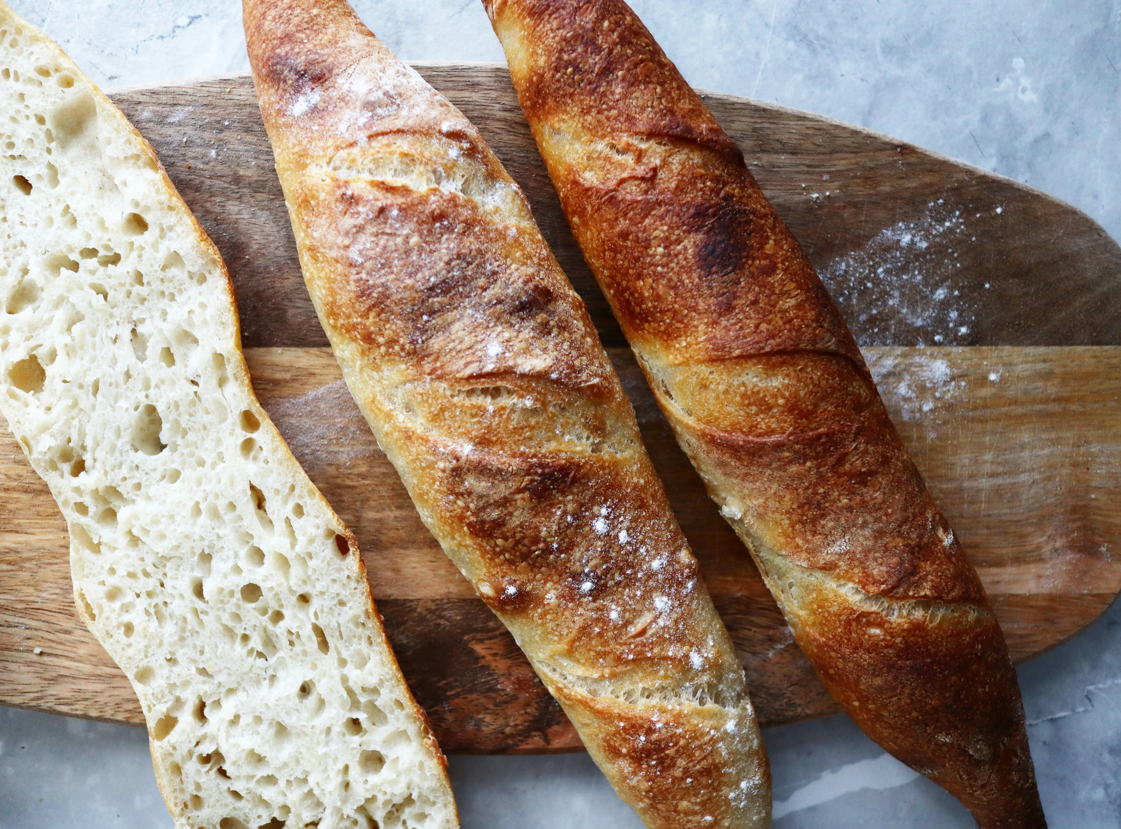 a pile of bread and two large loaves sitting on a  board