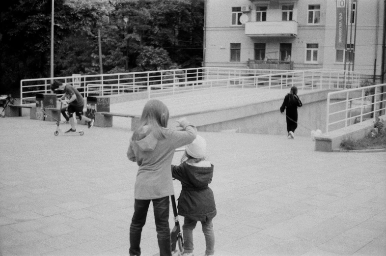 two children play and laugh together as the woman looks on