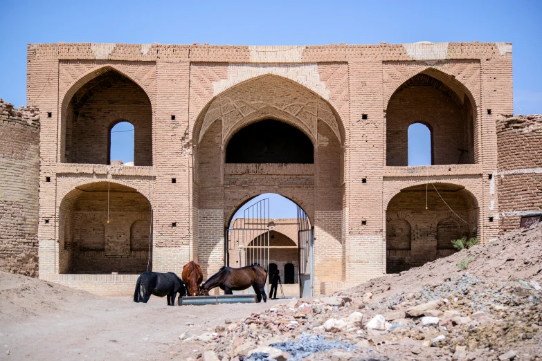 a pair of horses stand in a stone archway