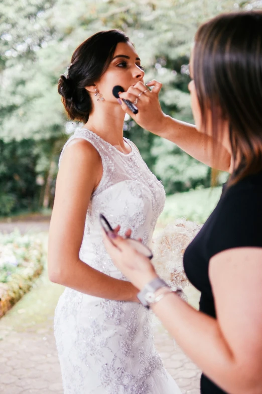 a bride has her make - up done before her wedding