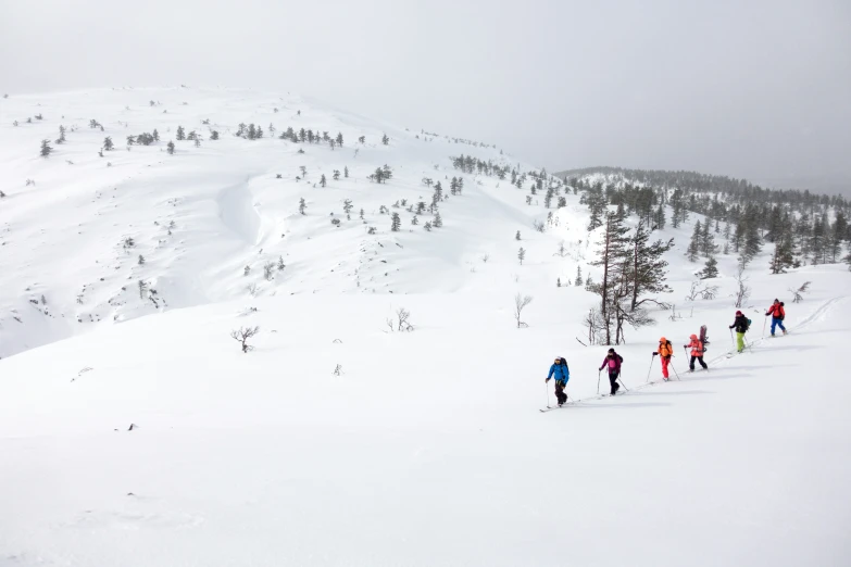 a group of people skiing down the side of a snow covered mountain