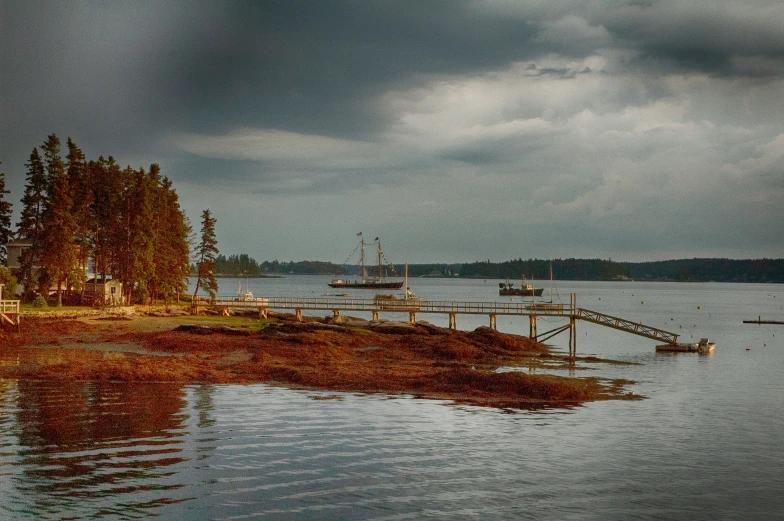 boats are floating on the water under a cloudy sky