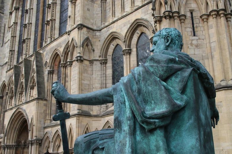 statue of an old man in front of a large building