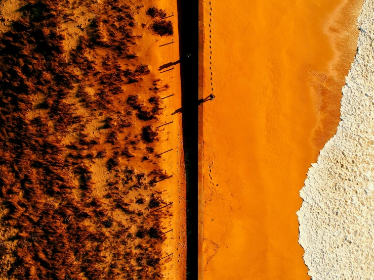 a yellow sand beach with water and a long sandy road