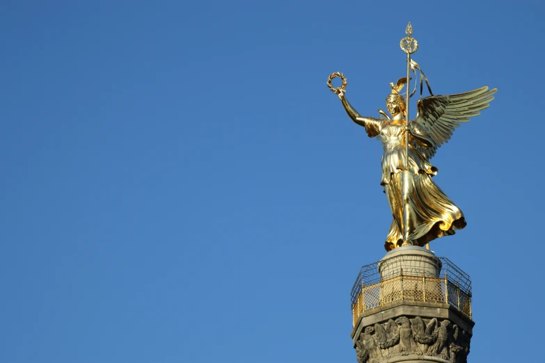 an ornately decorated golden statue atop a tower in a city