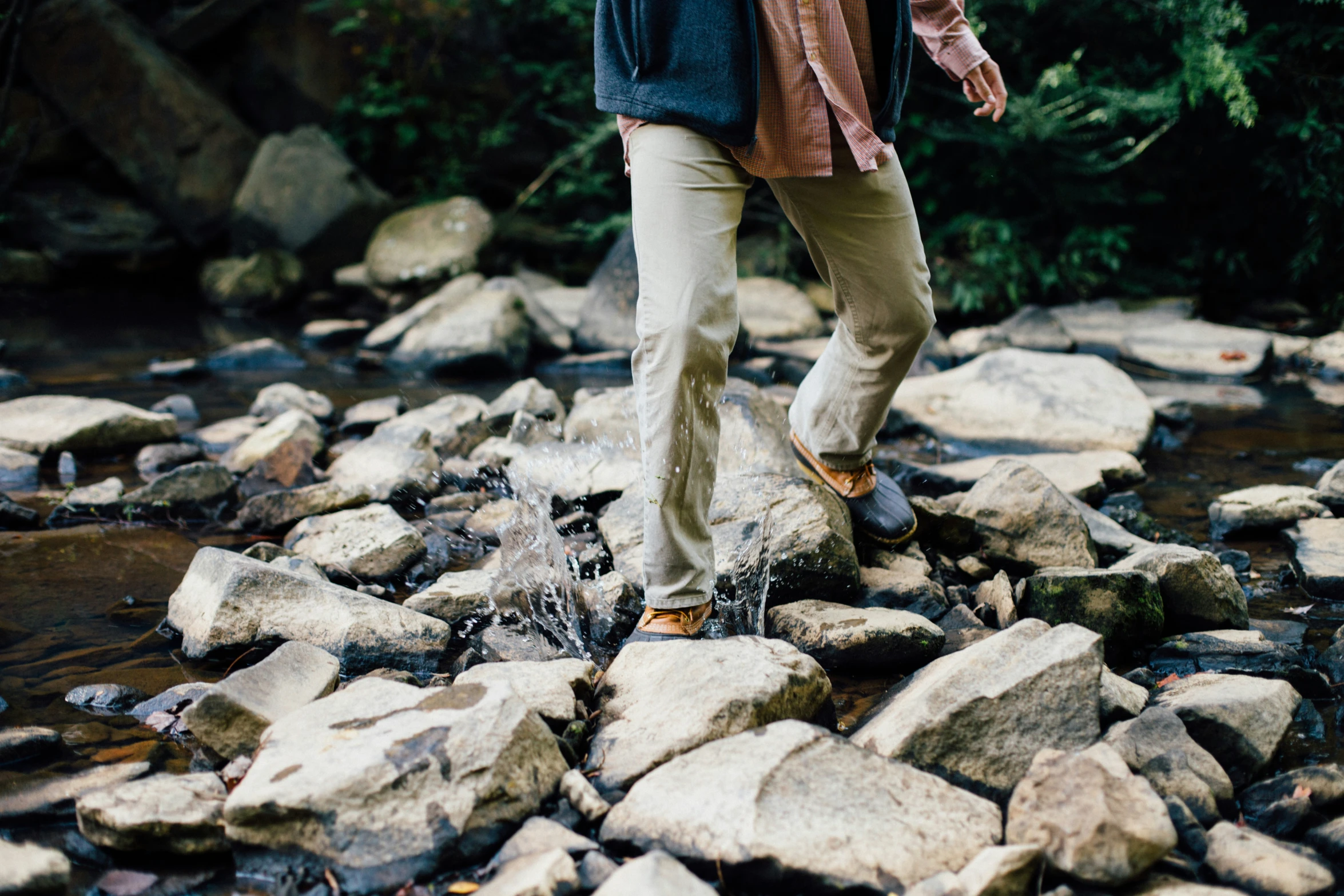 the guy is walking along the rocky bank