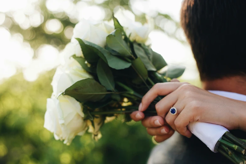 a person holding a bouquet of flowers, wearing a ring