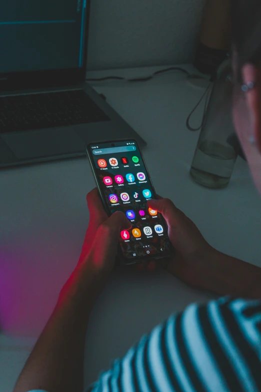 a person in front of a laptop with a phone