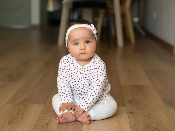 the baby girl is wearing her white pants and headband