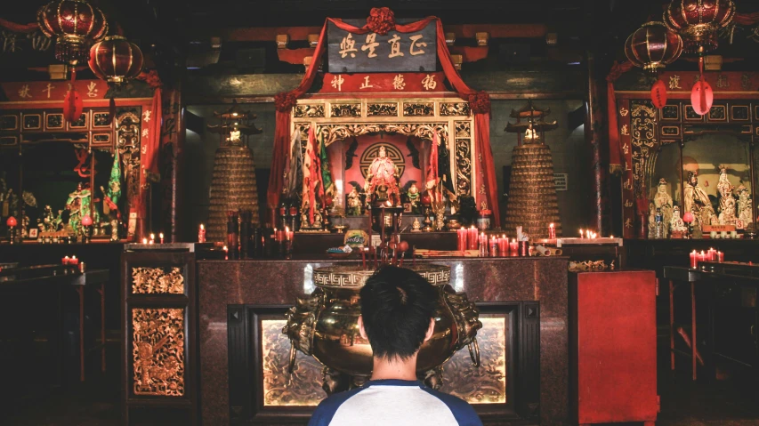 a  in a white shirt is looking into a shrine