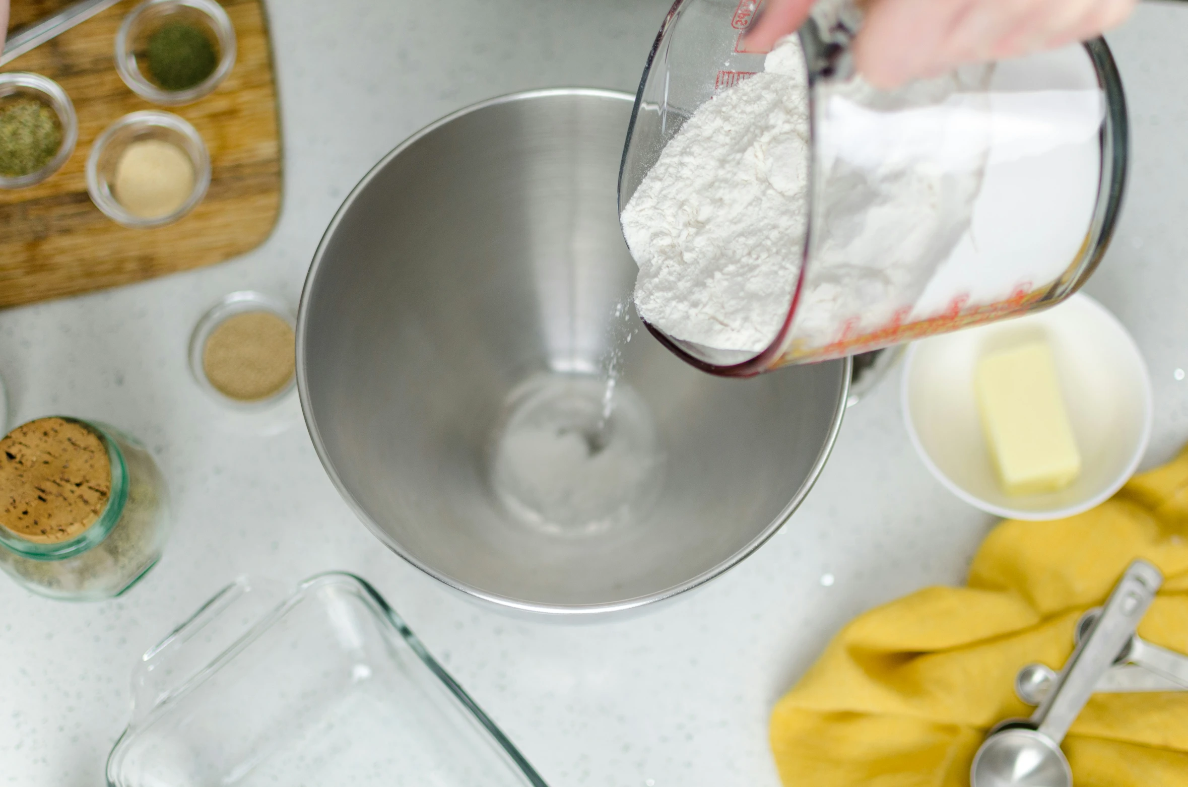 someone in the kitchen pouring ingredients into a bowl