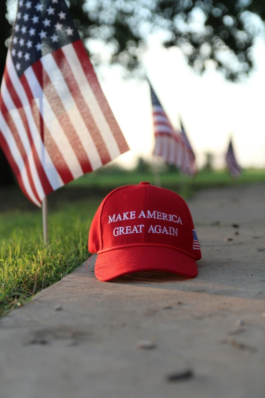 american flags are behind a red hat that reads make america great again