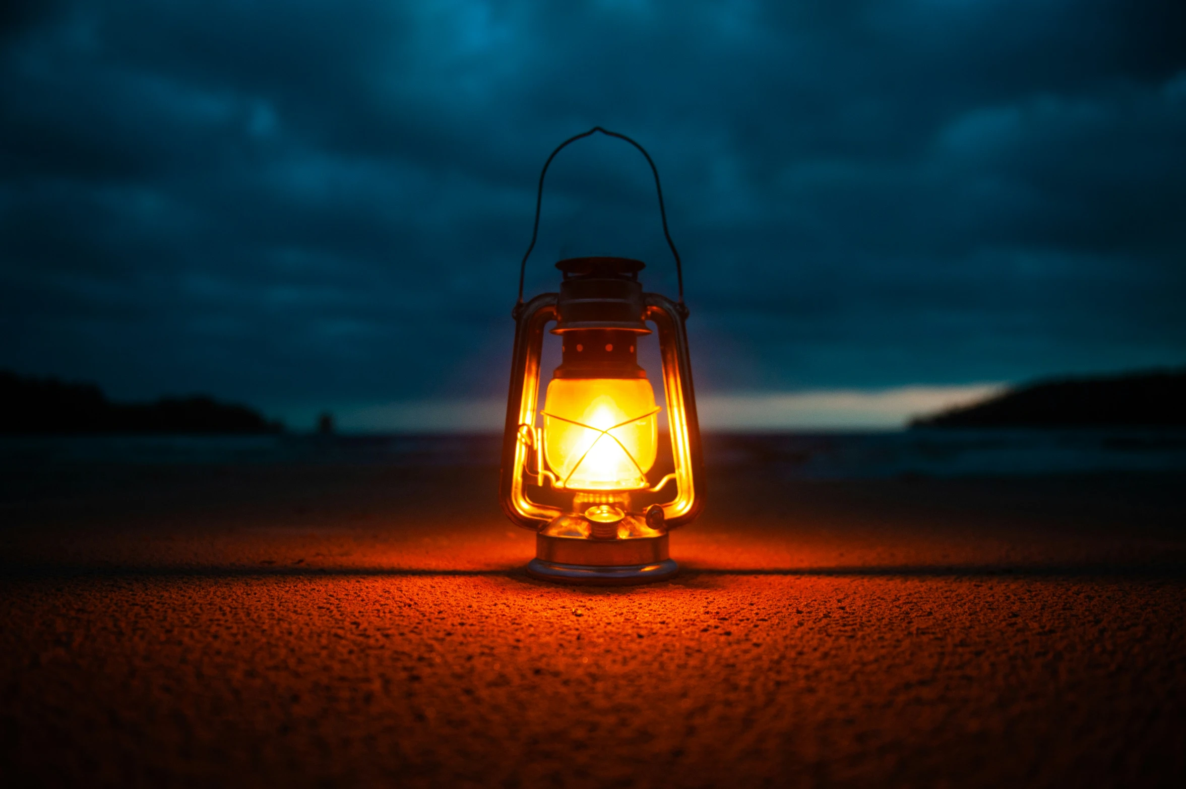 this is a lantern sitting on the sand under a cloudy sky