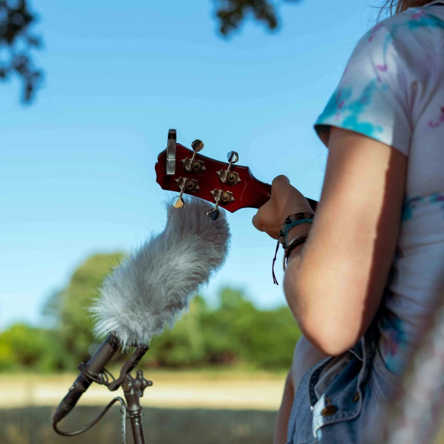 a woman playing a guitar that is in a microphone