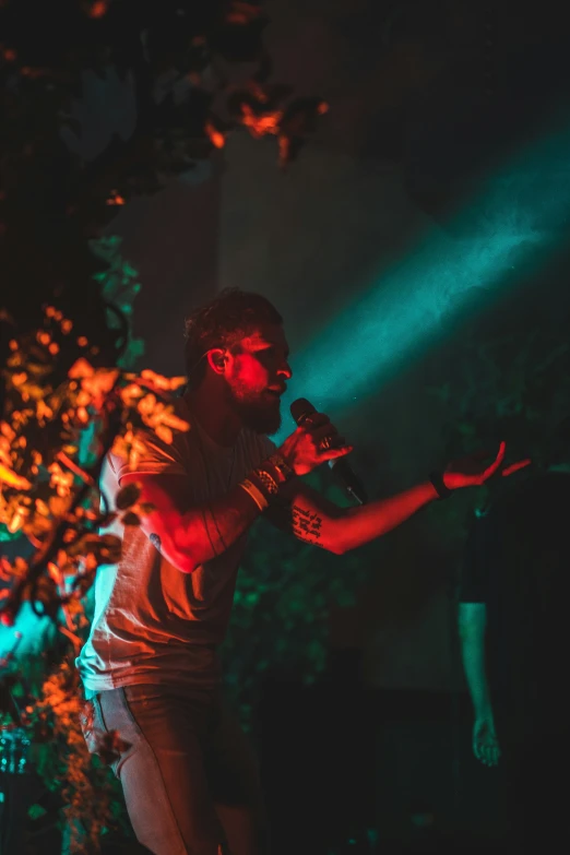 a man standing next to a tree while holding a microphone