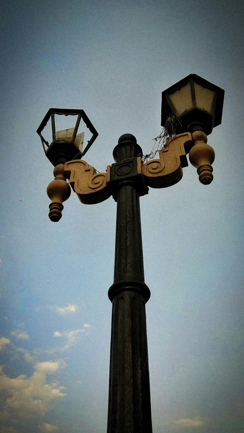 an old street light with two decorative lamps hanging from the end of it