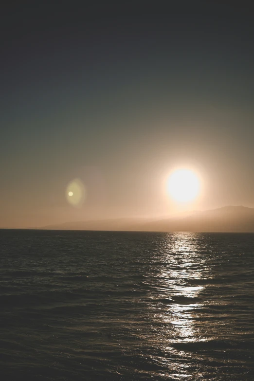 the sun is setting over the ocean with water